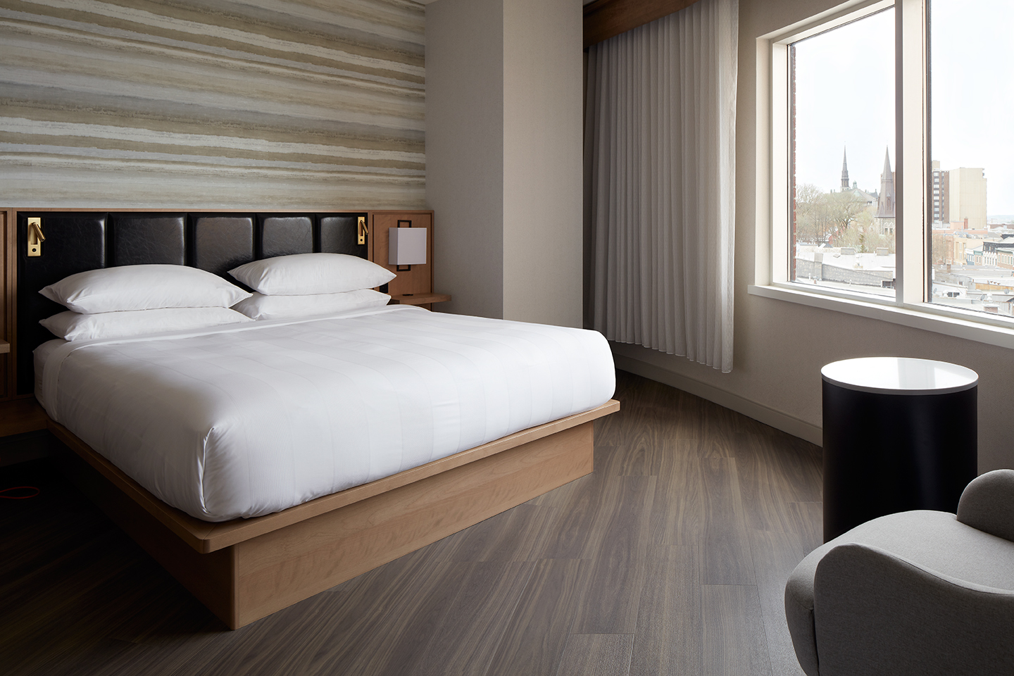 Photographie d'une chambre de l'hôtel Marriott Québec Centre-ville avec un lit double et une vue sur les toits du centre-ville de Québec.